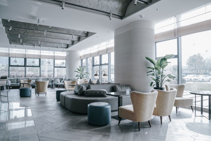 Modern commercial lobby with seating, large windows, and potted plants in a bright office space
